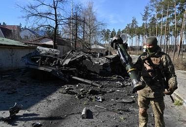 乌克兰士兵站在炸毁的俄罗斯装甲运兵车旁。