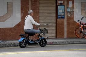 在芽笼一带，有位大叔将电动踏板车开上马路。PMD不能驶上马路，但偏偏还是有人以身试法.（海峡时报）