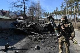 乌克兰士兵站在炸毁的俄罗斯装甲运兵车旁。